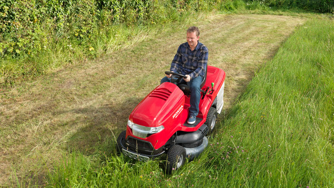 Prémiový záhradný traktor, predný trojštvrťový pohľad, zľava, počas prevádzky, na záhrade.
