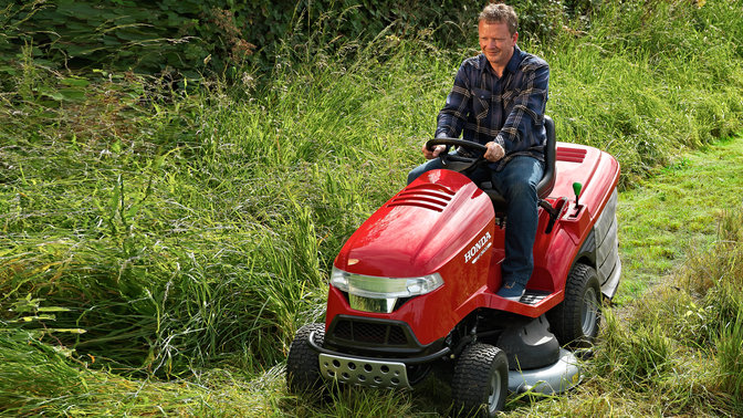 Predný trojštvrťový pohľad na prémiový záhradný traktor, zľava, počas prevádzky, na záhrade.