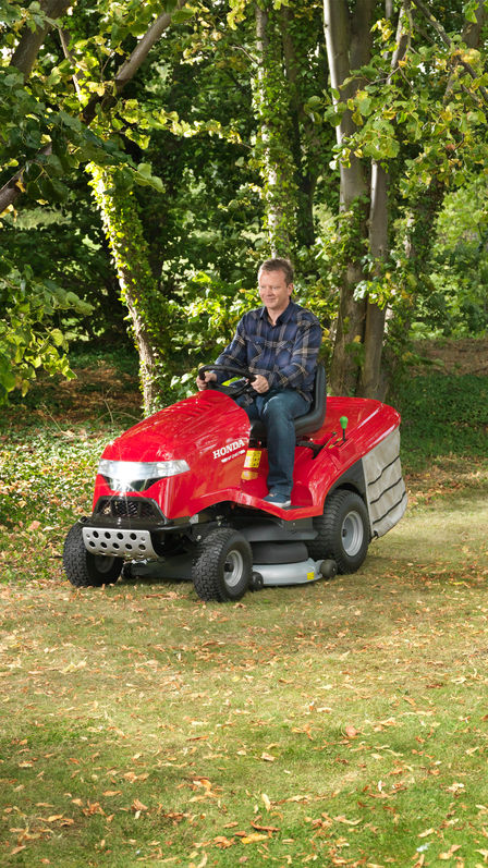 Prémiový záhradný traktor, predný trojštvrťový pohľad, zľava, počas prevádzky, na záhrade.