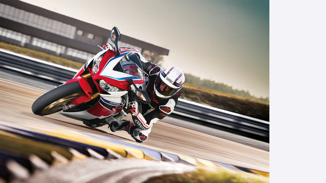 Predný 3/4 pohľad na model Fireblade s jazdcom, v zákrute na pretekárskom okruhu. Sprava.