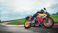 Predný 3/4 pohľad na model Honda CBR600RR s dizajnom Repsol, s jazdcom, sprava (pretekársky okruh).