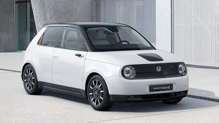 Trojštvrťový pohľad spredu na zaparkovaný model Honda e s budovou v pozadí