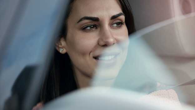 Detailný záber na ženu v pozerajúcu sa von otvoreným oknom vozidla