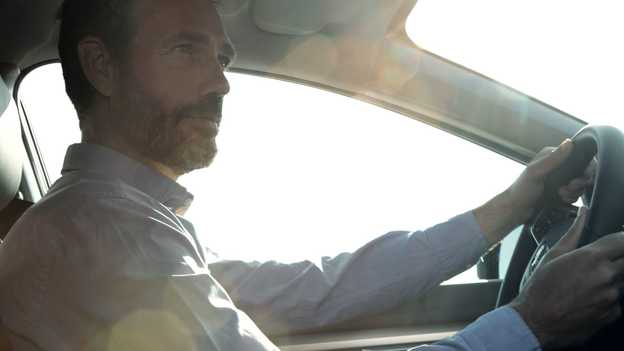 Detailný záber na muža sediaceho za volantom 