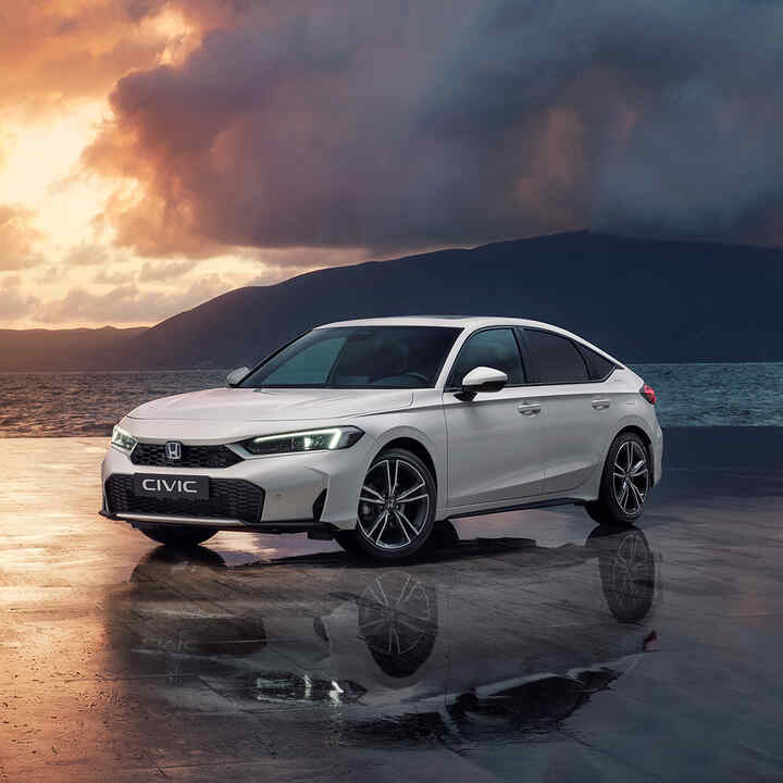 Civic Hybrid zaparkovaný pri oceáne pri západe slnka.