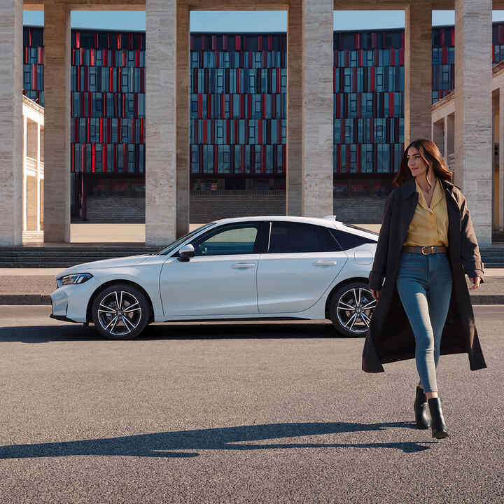 Dáma kráčajúca pred Civic Hybrid.