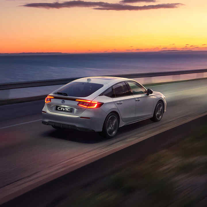 Vozidlo Civic Hybrid počas jazdy pri západe slnka.