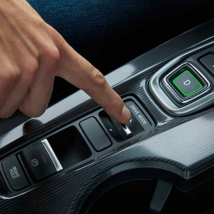 Detailný záber osoby vo vnútri Civicu Hybrid, ktorá nastavuje jazdný režim vozidla.