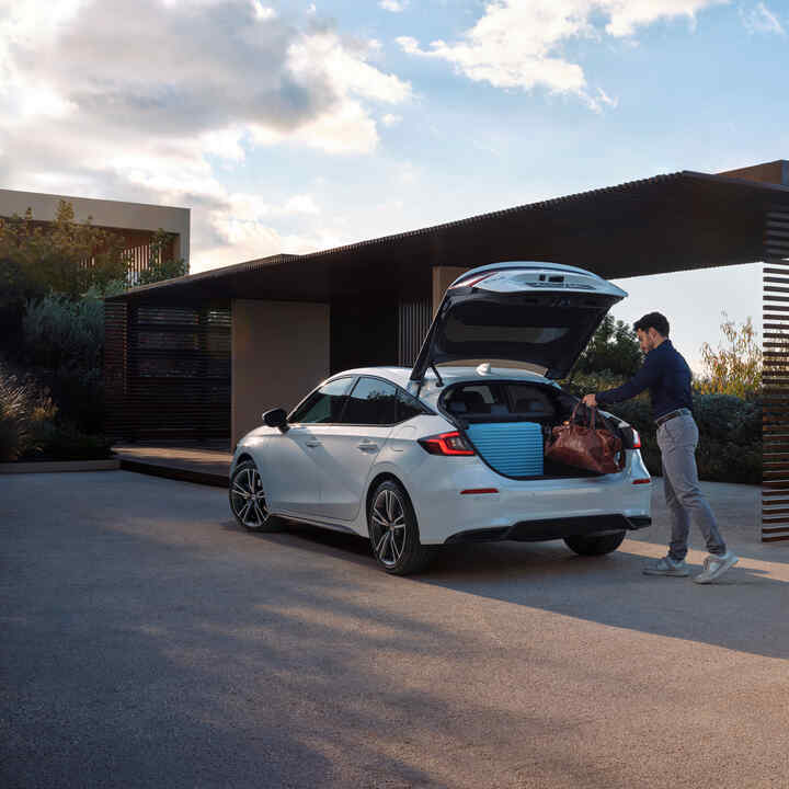 Osoba vkladá batožinu do kufra Civicu Hybrid.