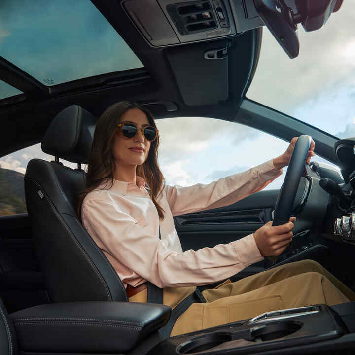 Žena v slnečných okuliaroch s rukami na volante Civicu Hybrid