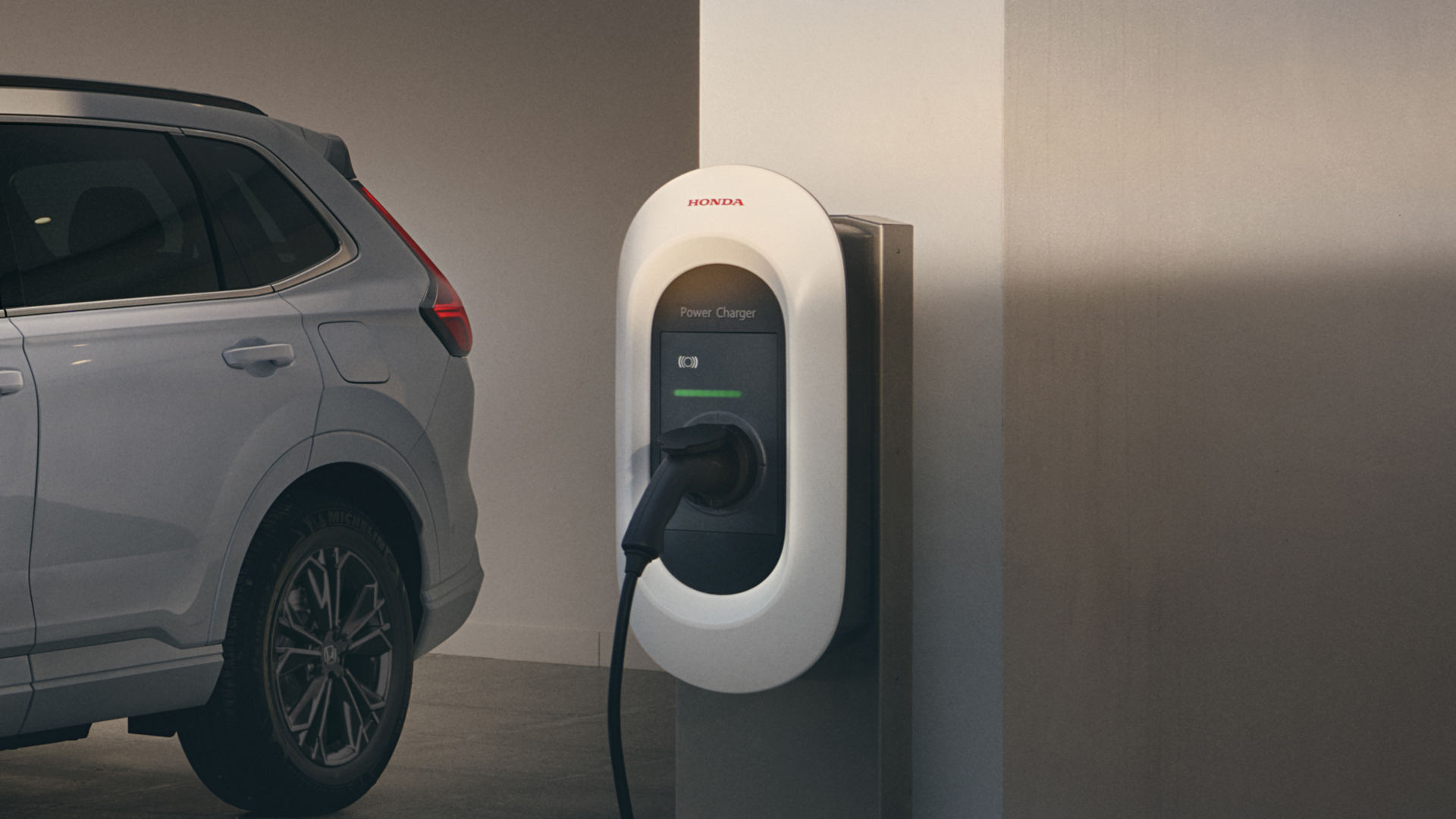 Trojštvrťový pohľad spredu na model Honda CR-V Hybrid pripojený k nabíjačke.