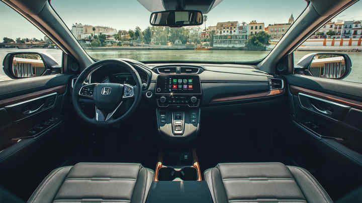 Pohľad na palubnú dosku v interiéri vozidla Honda CR-V Hybrid s širokým výhľadom na ulicu.