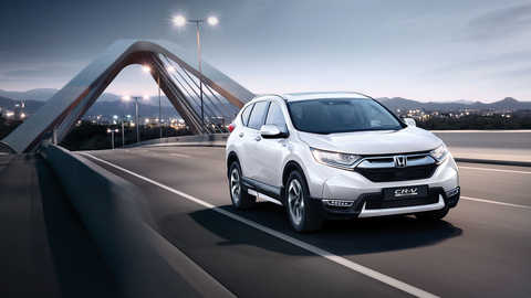 Trojštvrťový pohľad spredu na vozidlo Honda CR-V Hybrid idúce po ulici.