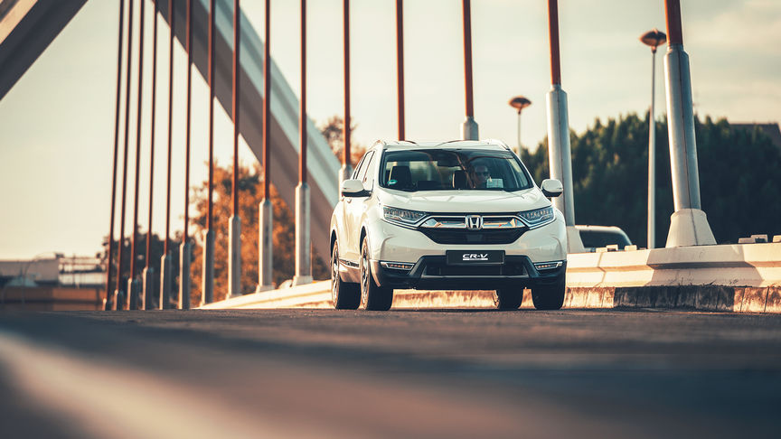 Trojštvrtinový pohľad spredu na vozidlo Honda CR-V Hybrid na ulici.