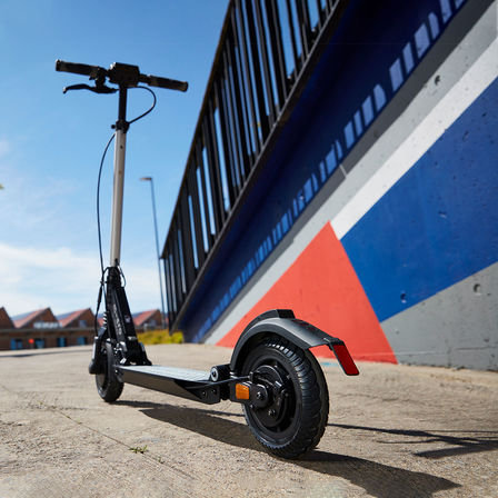 Kolobežka eSYMO zaparkovaná pri pestrofarebnom múre