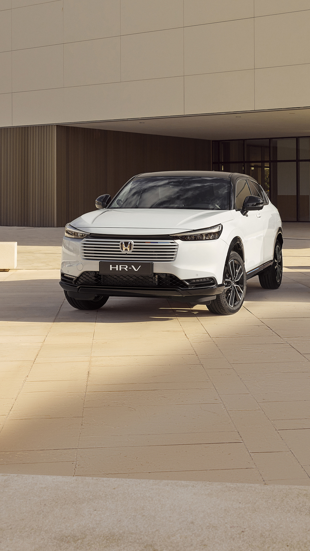 Two Honda HR-V SUVs parked outside a modern building, shown from front and rear angles—one in white facing forward and one in silver facing away.