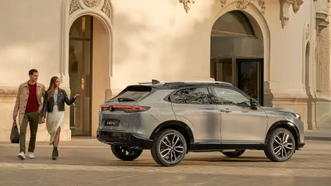 Honda HR-V zaparkovaná pred hotelom, s párom, ktorý prechádza okolo. 
