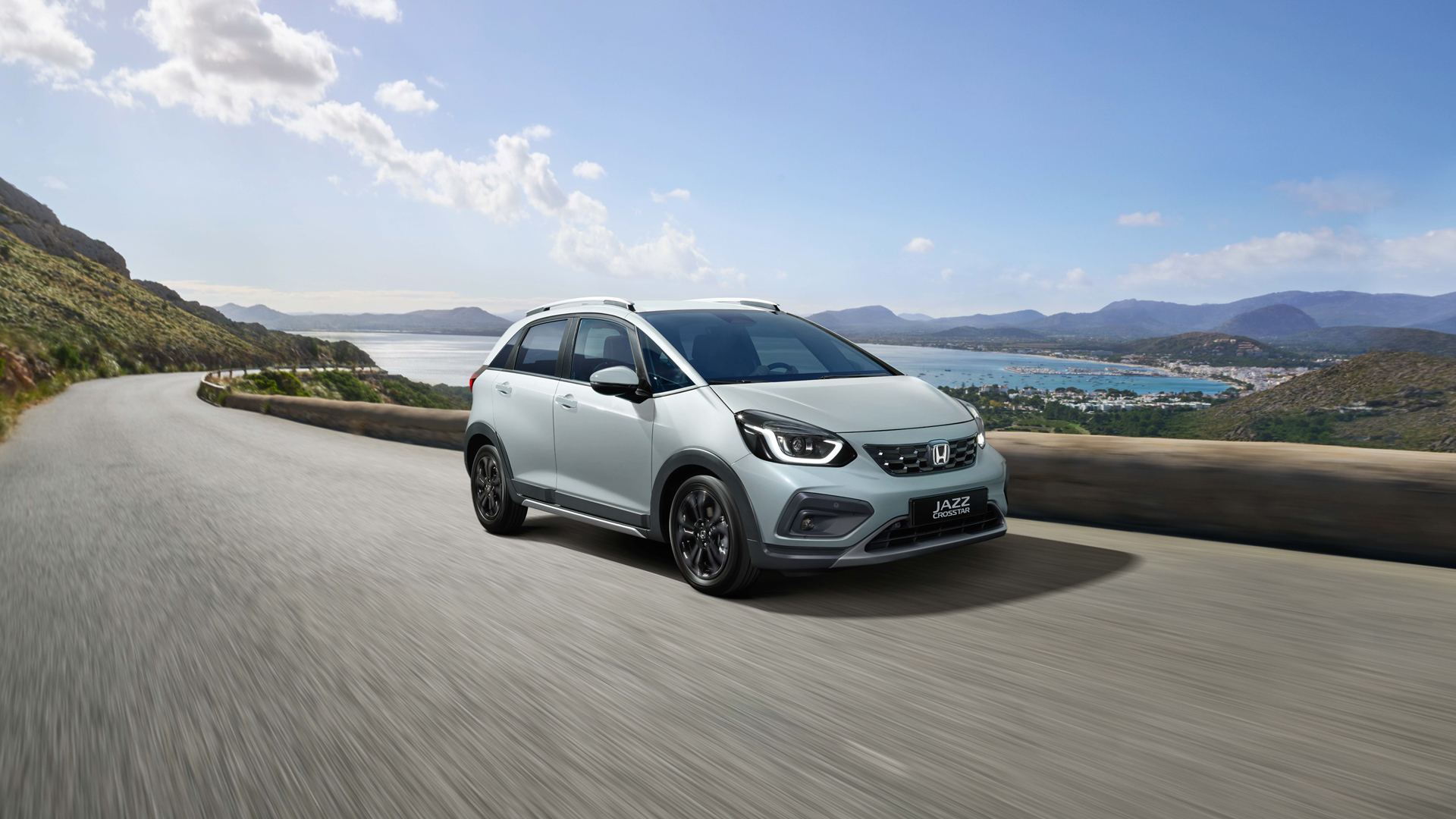 Trojštvrťový záber spredu na model Honda Jazz Hybrid s malebným výhľadom v pozadí.