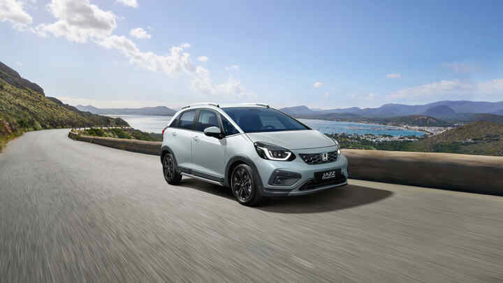 Trojštvrťový záber spredu na model Honda Jazz Hybrid s malebným výhľadom v pozadí.