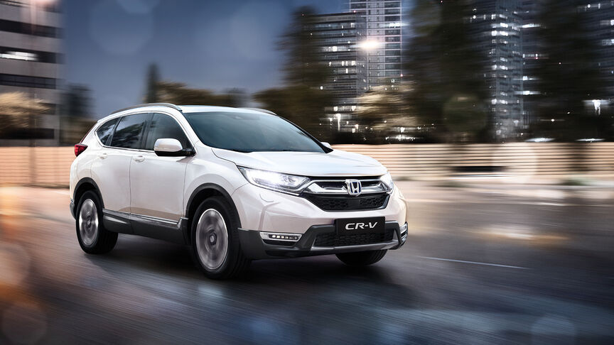 Trojštvrťový záber spredu na hybridný model HR-V pri jazde po vidieku