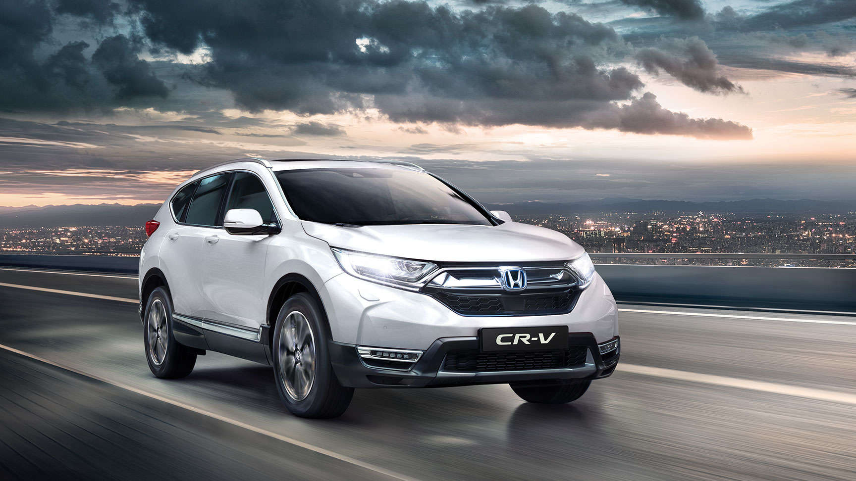 Predný trojštvrťový pohľad na model Honda CR-V so zapnutými diaľkovými svetlami
