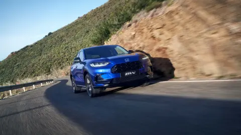 Vozidlo Honda ZR-V Hybrid SUV pri jazde po ceste v horách.