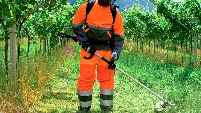 Figurant s krovinorezom neseným na chrbte v teréne.