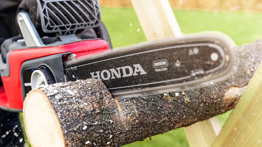 Detailný záber na figuranta pri rezaní dreva akumulátorovou reťazovou pílou Honda.