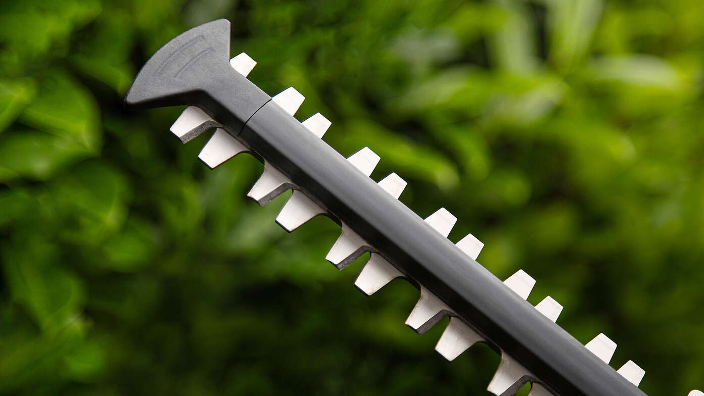 Bočný pohľad na akumulátorový plotostrih Honda v záhrade.