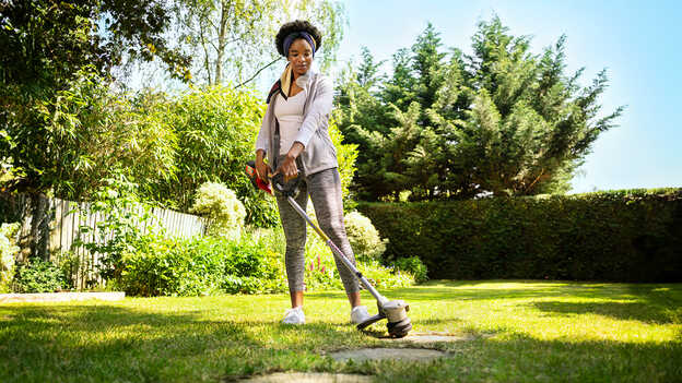 Žena používa akumulátorový vyžínač Honda na tráve v záhrade.
