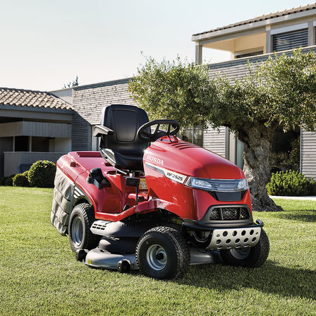 Trojštvrťový pohľad spredu na traktor Honda v záhrade s domom v pozadí