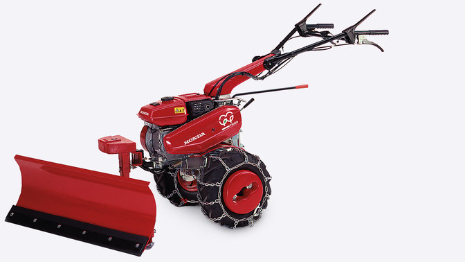 Bočn&yacute; pohľad na kompaktn&yacute; kultiv&aacute;tor so snežn&yacute;m pluhom.