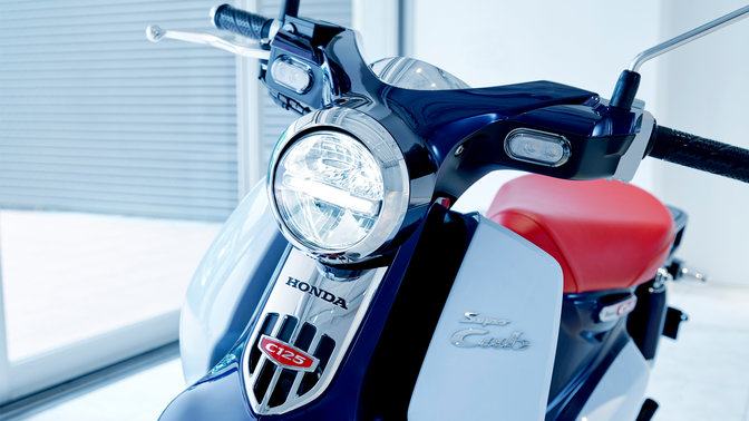 Model Honda Super Cub zaparkovaný v modernom prostredí.