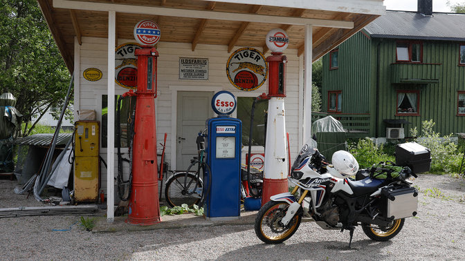 Motocykel zaparkovaný na čerpacej stanici mimo hlavnej cesty.