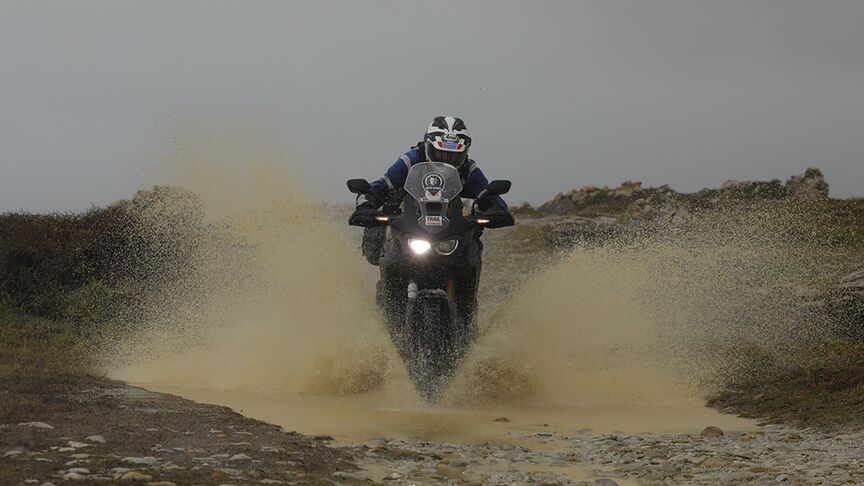 Motocyklový jazdec prechádzajúci náročným terénom Južnej Afriky.