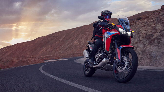 Figurant idúci na motocykli CRF1100L Africa twin na ceste v horách.