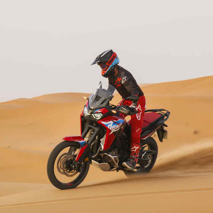 Figurant idúci na motocykli CRF1100L Africa Twin po ceste v púšti.
