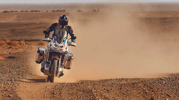 záber spredu na jazdca na motocykli Honda CRF1100 Africa Twin Adventure Sports v púšti.