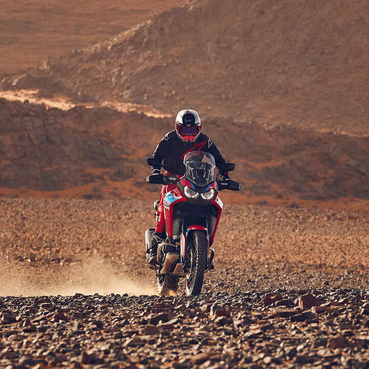 Trojštvrťový pohľad spredu na jazdca na motocykli CRF1100 Africa Twin Adventure Sports v teréne.