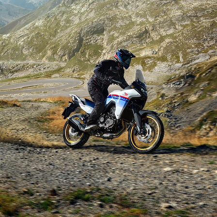 Model XL750 Transalp na šotolinovej ceste s horami v pozadí.