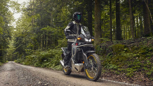 Model jazdiaci na Honde XL750 Transalp v lese.