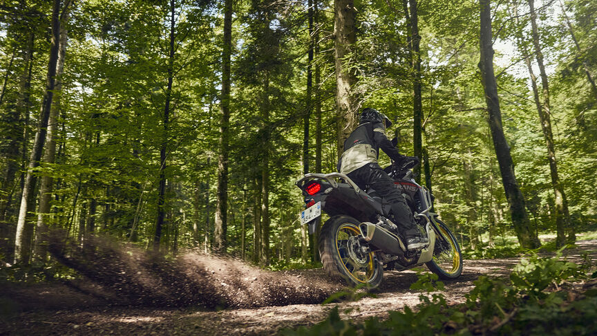 Figurant pri jazde na motocykli XL750 Transalp v lese.
