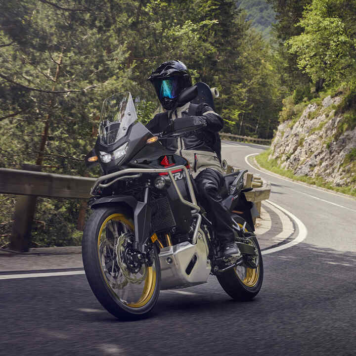 Model jazdiaci na motocykli XL750 Transalp v horskom prostredí.