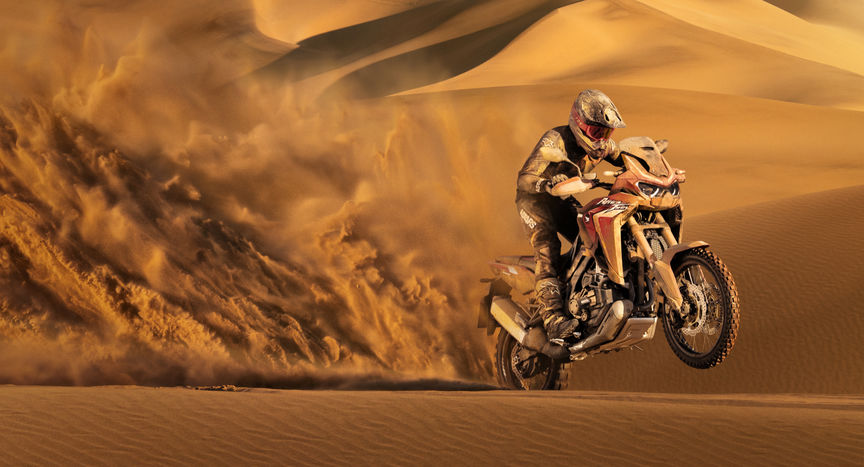 Trojštvrťový predný záber z pravej strany na model Honda Africa Twin pri jazde v piesku