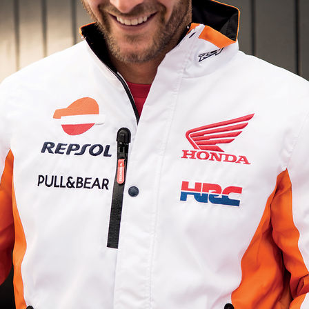 Usmievajúci sa muž s pretekárskou bundou Honda.