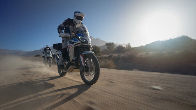 Dvaja jazdci HAR v teréne s horami v pozadí