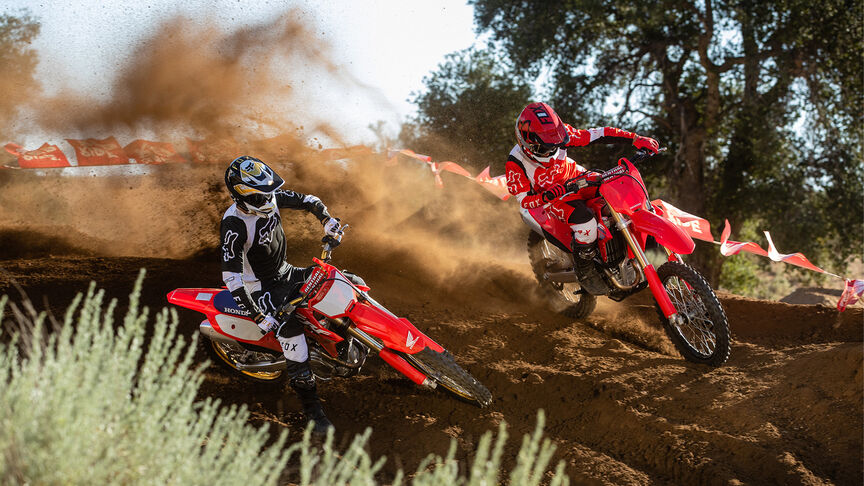 Dvaja jazdci prekonávajú úseky so skokmi na modeloch Honda CRF450R.