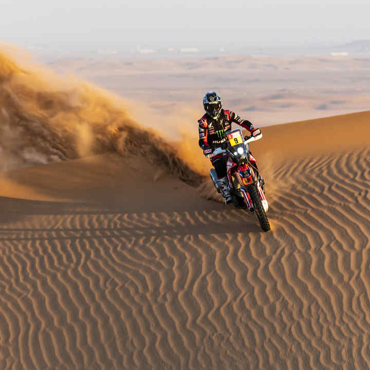 Jazdec Honda na rely Dakar v púštnych dunách. 