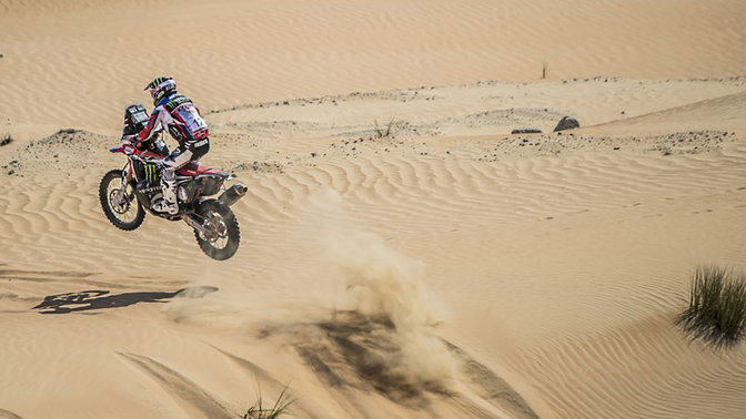 Pohľad zozadu na natočený model Honda CRF450 pri jazde po piesočných dunách.