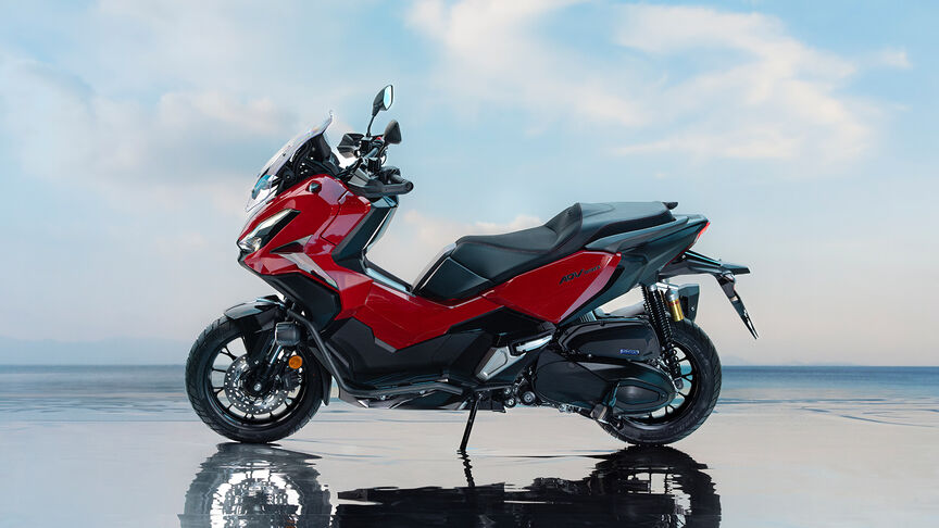 Trojštvrťový záber spredu na skúter Honda ADV350 na pobreží.